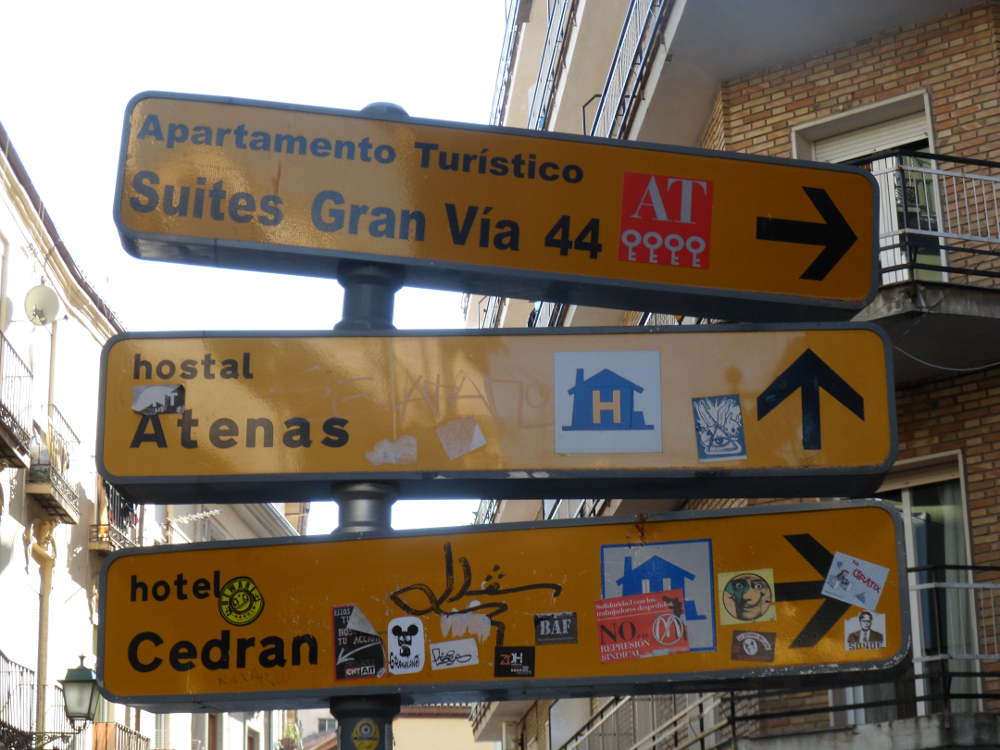 Señalización hotelera adornada con toda clase de pegatinas en calle Elvira esquina a Cedrán.