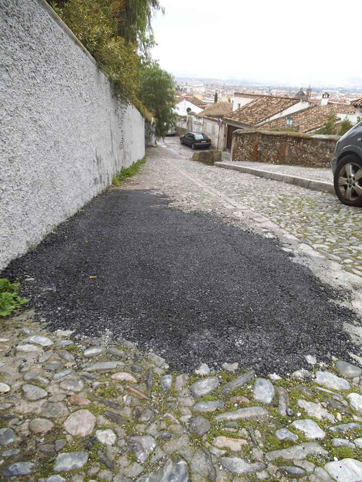 Los baches en el empedrado se rellenan de asfalto en la calle Zenete.  2014