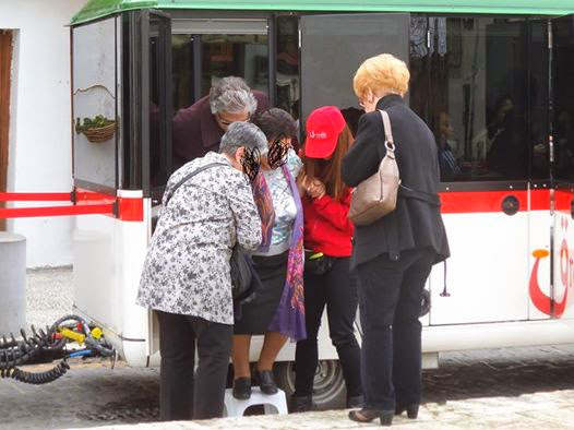 Una persona mayor necesita la banqueta de plástico y la ayuda de varias personas para bajar del tren turístico.