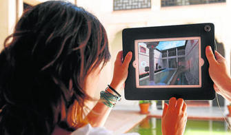 Una pareja de visitantes hacen uso del Ipad en el patio para contemplar a través de la pantalla cómo era una casa tipo nazarí basada en Zafra.